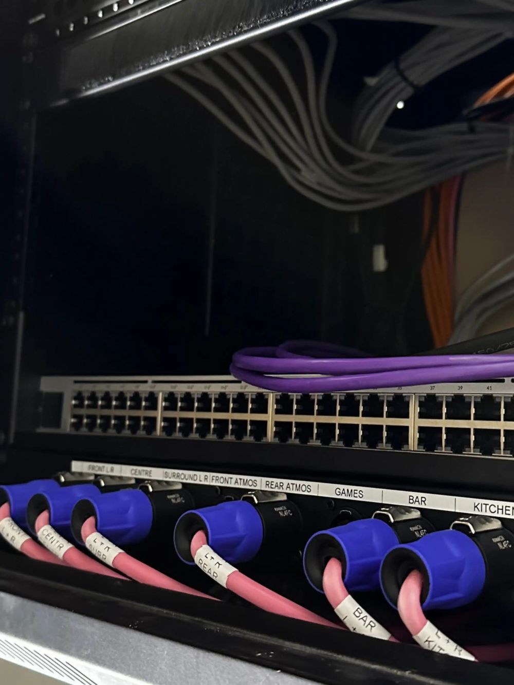 Equipment rack with labelled speaker connections for front, centre, surround and Atmos channels